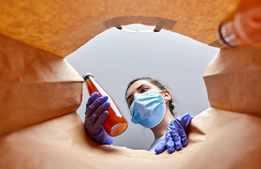 Image showing woman in gloves and mask with food in paper bag