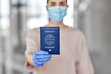 Image showing woman in mask and gloves holding immunity passport