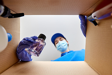 Image showing woman in mask packing parcel box with cosmetics