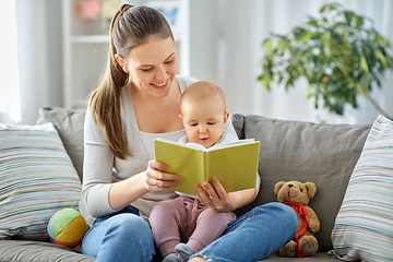 Image showing happy mother reading book to little baby at home