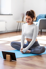 Image showing young woman with tablet pc doing yoga at home