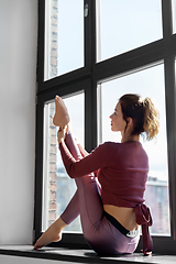 Image showing woman doing yoga exercise on window sill at studio