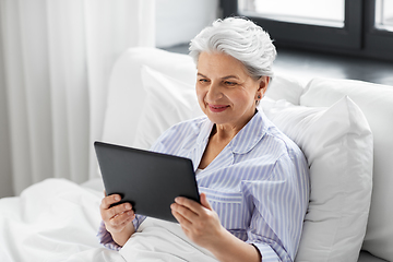 Image showing senior woman with tablet pc in bed at home bedroom