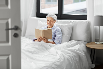 Image showing senior woman reading book in bed at home bedroom