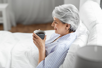 Image showing old woman with cup of coffee in bed at home