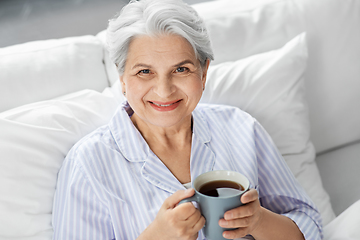 Image showing old woman with cup of coffee in bed at home