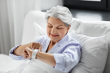 Image showing happy senior woman sitting in bed at home bedroom