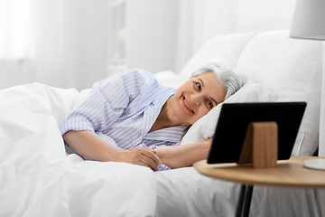 Image showing happy senior woman with tablet pc in bed at home