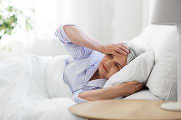 Image showing senior woman with headache in bed at home