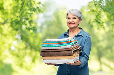 Image showing smiling senior woman with clean bath towels