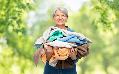 Image showing smiling senior woman with heap of bath towels