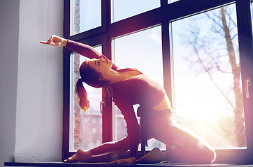 Image showing woman doing yoga exercise on window sill at studio