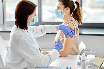 Image showing female doctor with syringe vaccinating patient