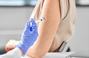 Image showing female doctor with syringe vaccinating patient