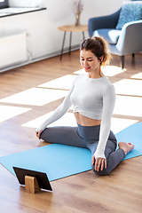 Image showing young woman with tablet pc doing yoga at home