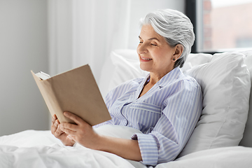 Image showing senior woman reading book in bed at home bedroom