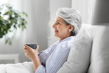 Image showing old woman with cup of coffee in bed at home