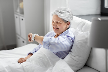 Image showing happy senior woman sitting in bed at home bedroom