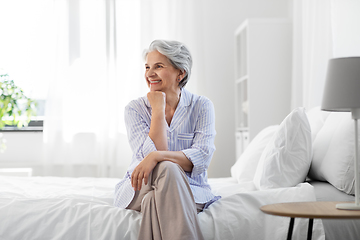 Image showing happy senior woman sitting on bed at home bedroom