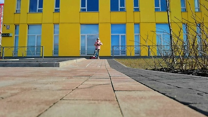 Image showing Cute young girl playing on a push scooter outdoors