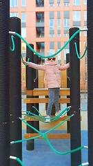 Image showing girl plays on the rope park playground. The concept of children's rest in an urban environment.