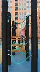 Image showing girl plays on the rope park playground. The concept of children's rest in an urban environment.