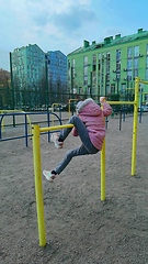 Image showing little girl hanging on a sports horizontal bar on the street near the house. child playing in the playground