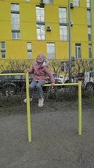 Image showing little girl hanging on a sports horizontal bar on the street near the house. child playing in the playground
