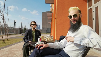 Image showing Two young hipster guy sitting in a cafe chatting and drinking coffee smiling