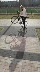 Image showing Tilt up shot of stylish Caucasian businessman riding bicycle along city street in downtown while going to office in the morning.