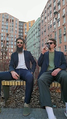 Image showing Two young men friends dressed casually spending time together at the city, drinking takeaway coffee next bike.