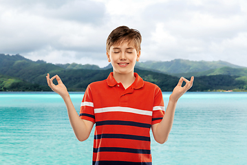 Image showing happy smiling meditating boy over hills and ocean