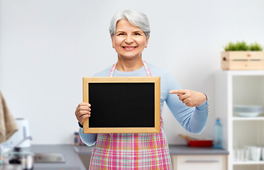 Image showing smiling senior woman with chalkboard at kitchen