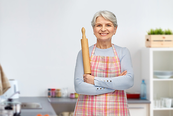 Image showing smiling senior woman with rolling pin at kitchen