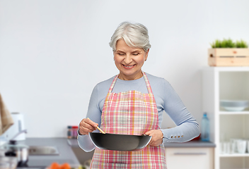 Image showing smiling senior woman with frying pan at kitchen