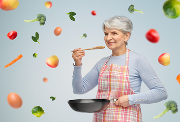 Image showing smiling senior woman in apron with frying pan