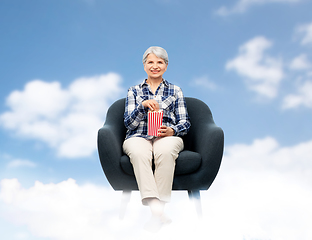 Image showing senior woman eating popcorn sitting in armchair