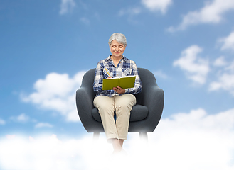 Image showing smiling senior woman in armchair writing to diary