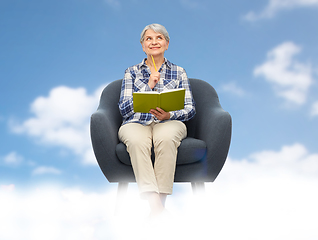 Image showing smiling senior woman in armchair writing to diary