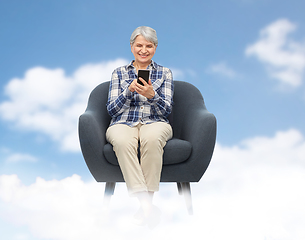 Image showing smiling senior woman with smartphone in chair