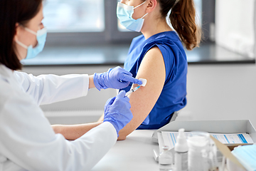 Image showing doctor with syringe vaccinating medical worker