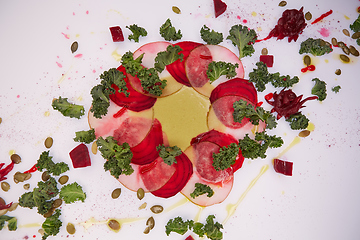 Image showing Carpaccio of beet and pear with pumpkin seeds decorated with sauce and green leaves.