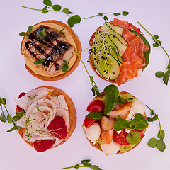 Image showing four different bruschettes with salmon, mackerel, shrimp and halibut.