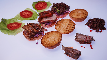 Image showing Three open burgers with different fillings with a torn pork, with ribs and pork ribs on a white table