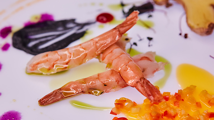 Image showing three prawns on a white table decorated with chopped vegetables and sauce.