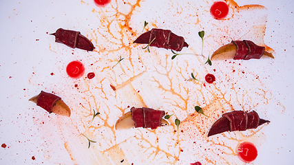 Image showing Prosciutto with pear on white table. Traditional Mediterranean snack