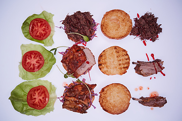 Image showing Three open burgers with different fillings with a torn pork, with ribs and pork ribs on a white table