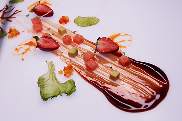 Image showing Conceptual Salad of Salmon and Avocado Cubes. Decorated with sauce, strawberries and green leaves