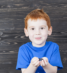 Image showing red-haired boy holds blueberry