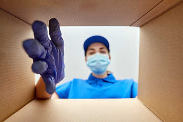 Image showing woman in mask looking inside cardboard parcel box